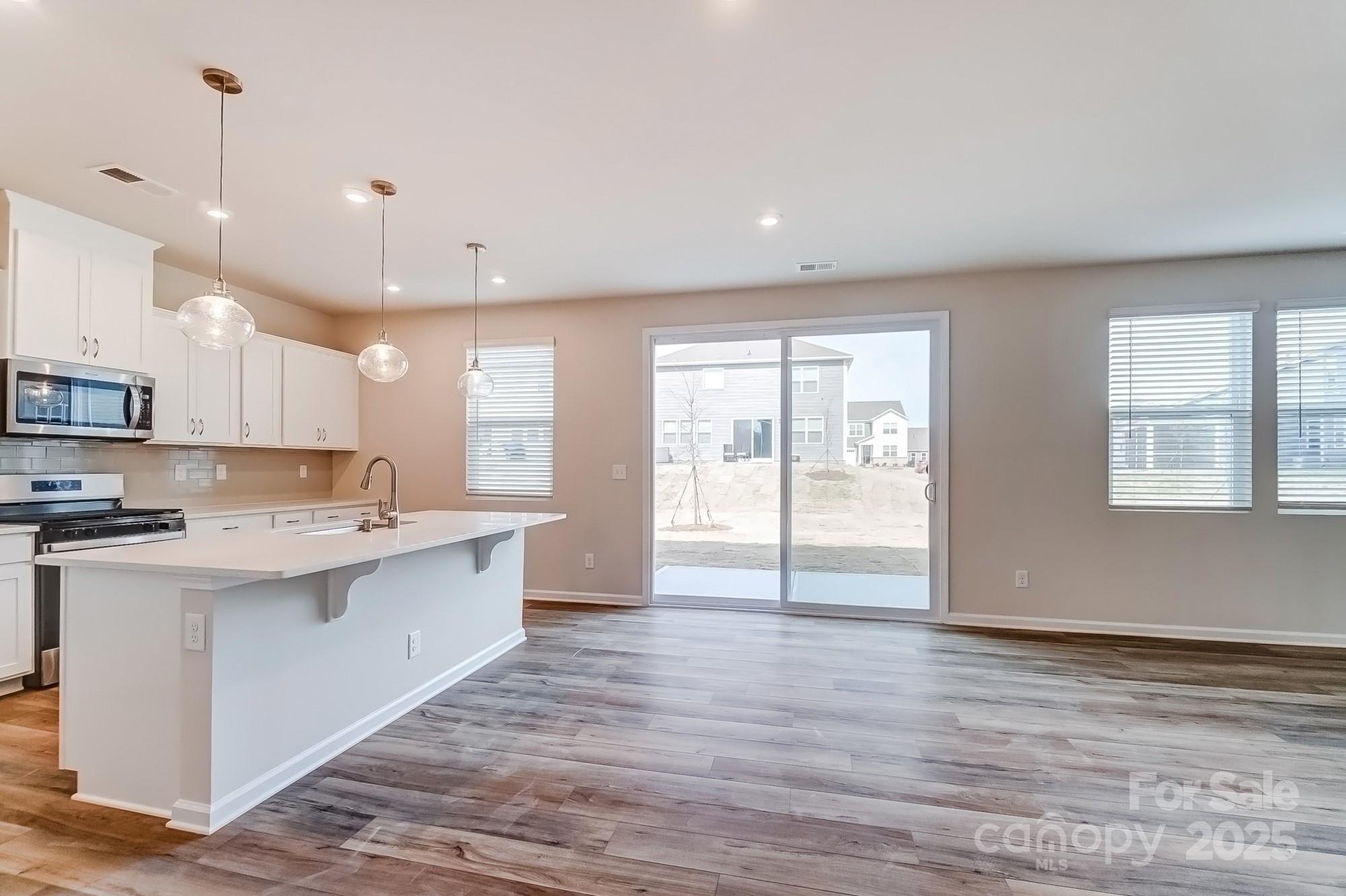1471 Honey Trail Monroe, NC 28112 - Photo 10 of 27 a large kitchen with stainless steel appliances kitchen island a large counter top and a wooden floors