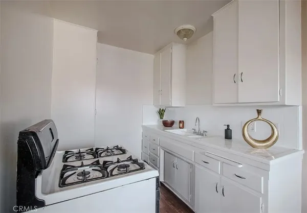a white kitchen with sink a stove and cabinets