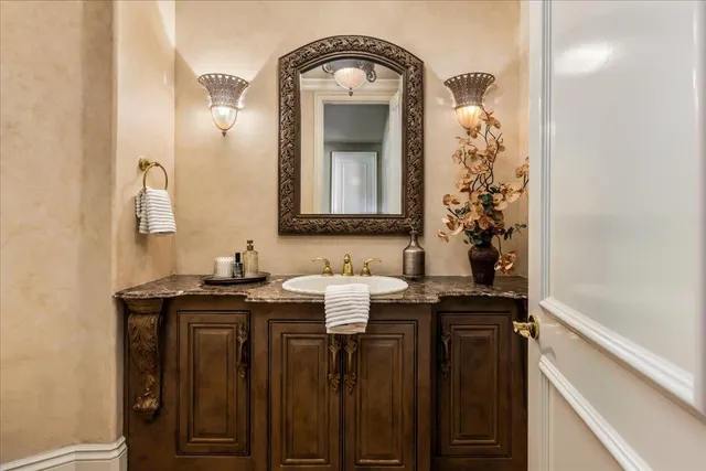 a bathroom with a granite countertop sink and a large mirror