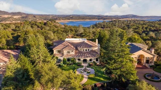a front view of a house with a garden and lake view