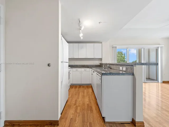 a kitchen with stainless steel appliances granite countertop a refrigerator sink and white cabinets