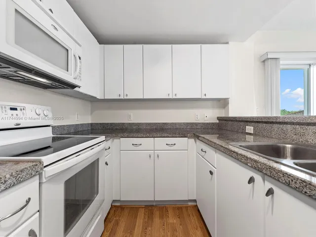 a kitchen with granite countertop white cabinets and white appliances