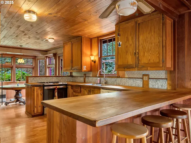 a kitchen with stainless steel appliances granite countertop a stove top oven a sink a dining table and chairs with wooden floor