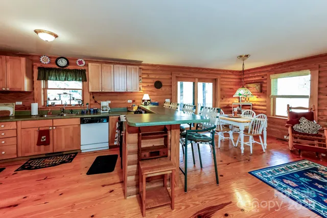 a kitchen with stainless steel appliances a stove a refrigerator a dining table and chairs with wooden floor