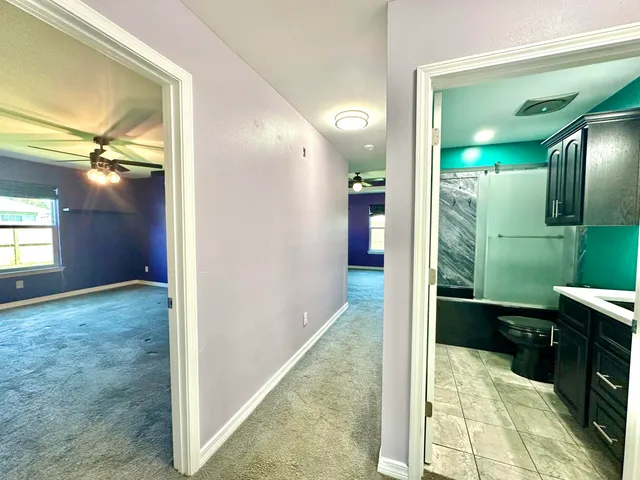 an empty room with windows and ceiling fan