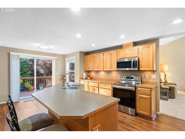 a kitchen with stainless steel appliances granite countertop a sink a stove and a refrigerator with wooden floor
