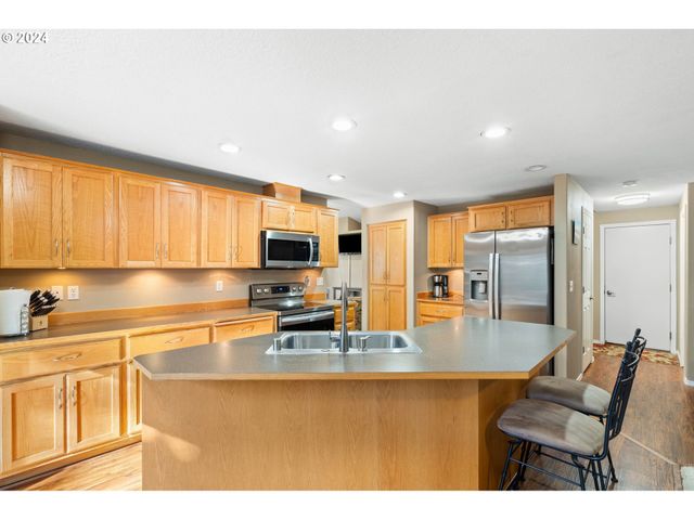 a kitchen with stainless steel appliances granite countertop a refrigerator a sink dishwasher a stove and white countertops with wooden floor