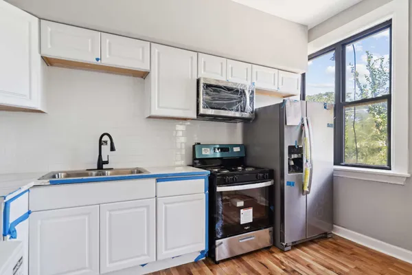 a kitchen with stainless steel appliances a sink cabinets and a window