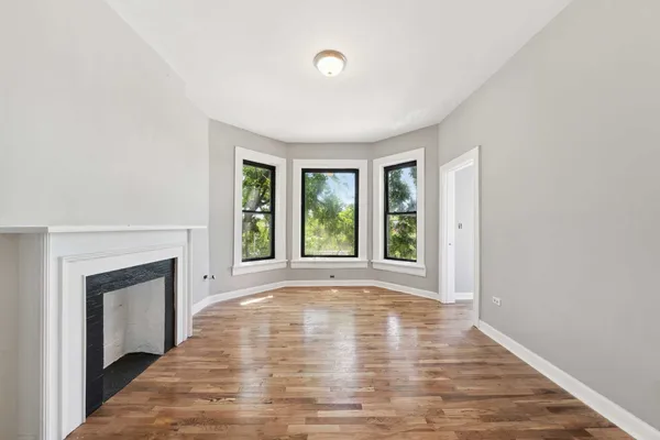 a view of empty room with wooden floor and fireplace