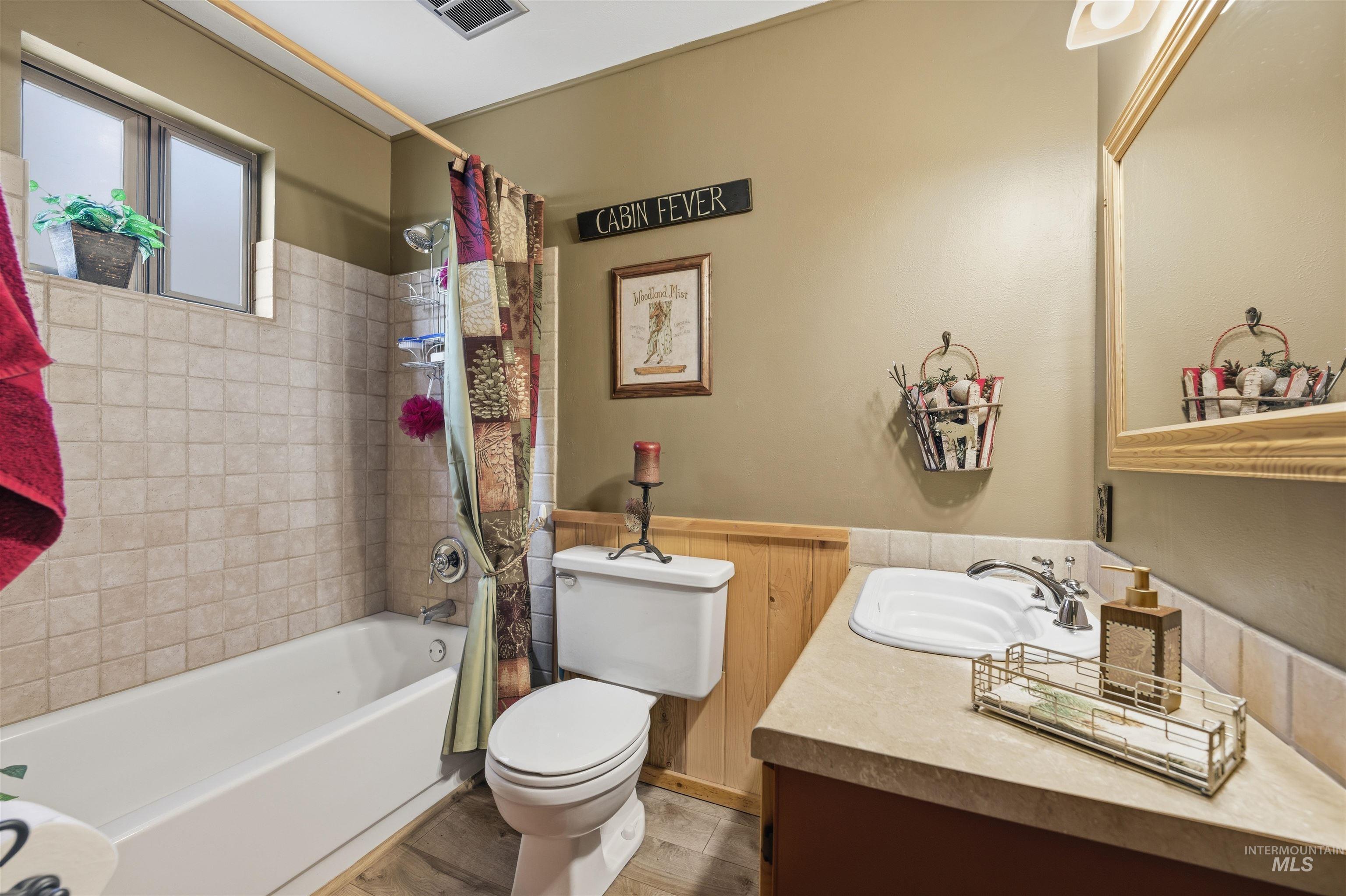 45 Rainbow Ridge Road Garden Valley, ID 83622 - Photo 19 of 41 Bathroom featuring shower / bathtub combination with curtain, vanity, a wainscoted wall, and light wood finished floors