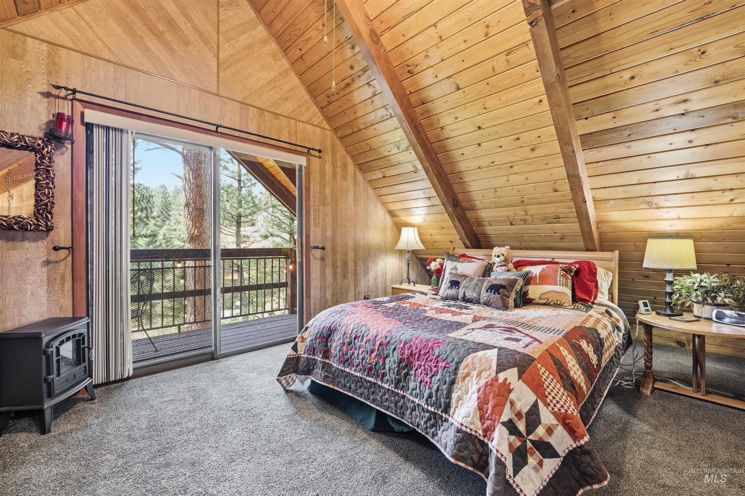45 Rainbow Ridge Road Garden Valley, ID 83622 - Photo 27 of 41 Bedroom with wood ceiling, carpet flooring, wood walls, access to outside, and vaulted ceiling with beams
