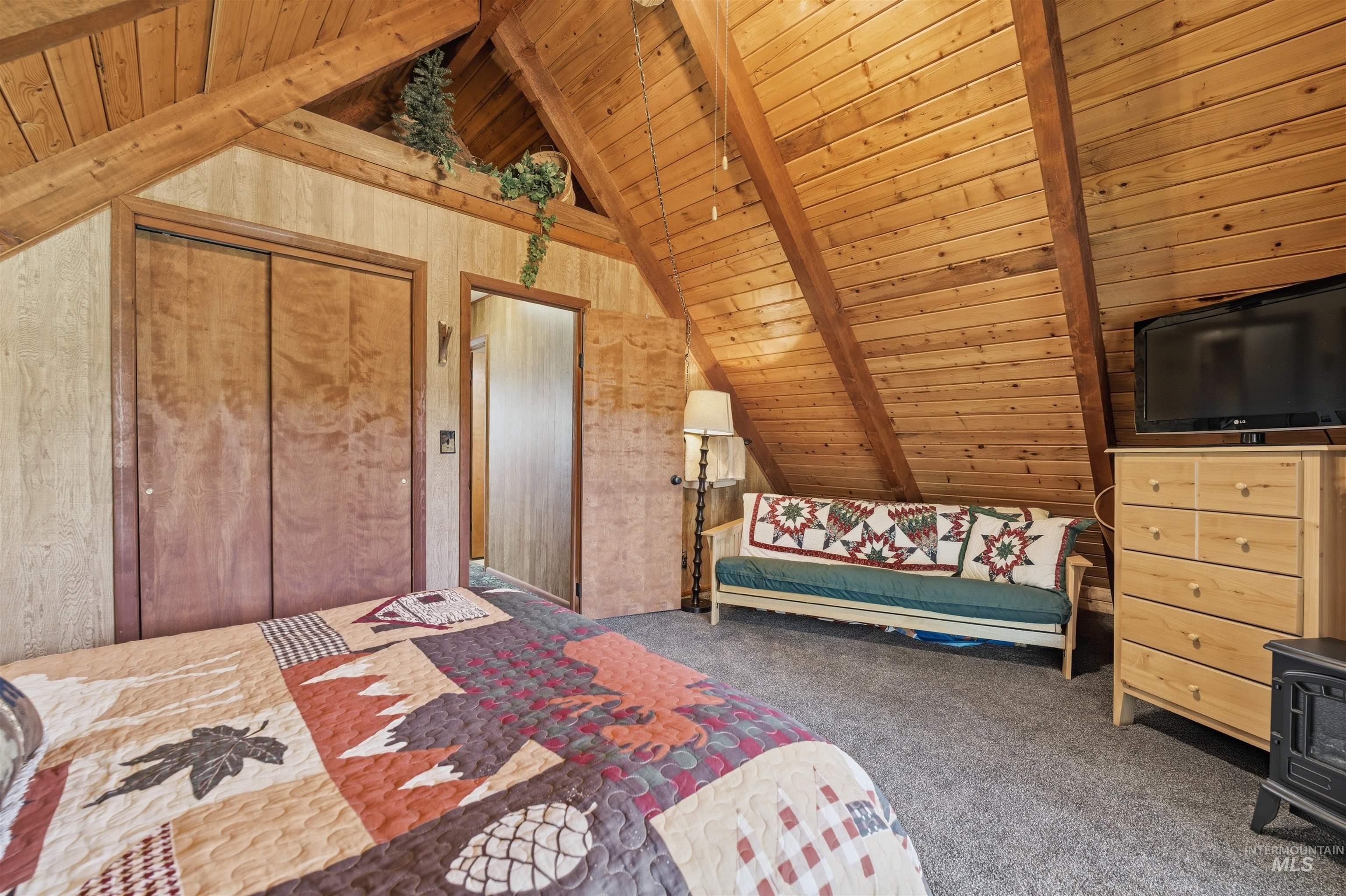 45 Rainbow Ridge Road Garden Valley, ID 83622 - Photo 28 of 41 Carpeted bedroom featuring a wood ceiling with exposed beams, wood walls, and a closet