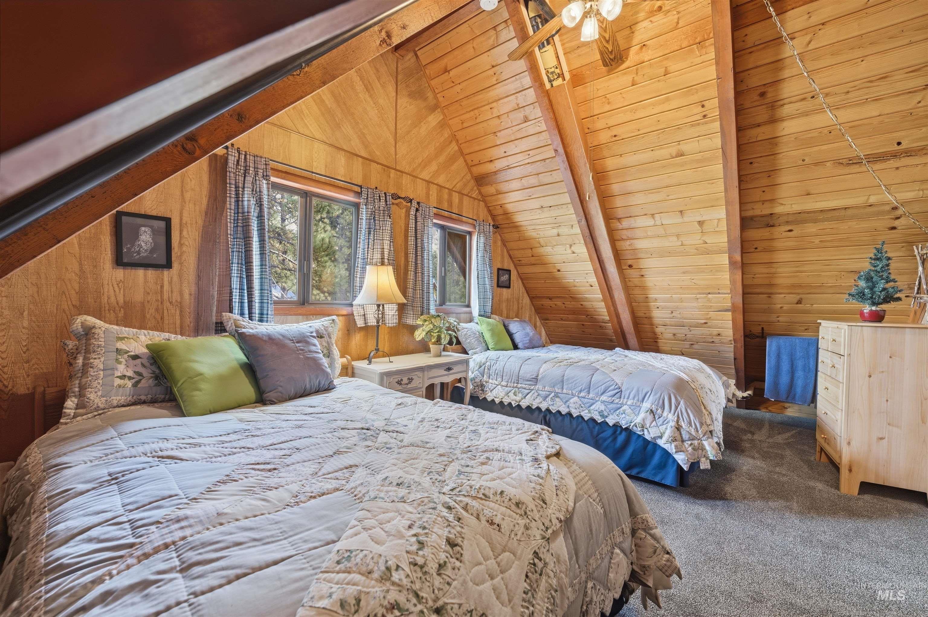 45 Rainbow Ridge Road Garden Valley, ID 83622 - Photo 31 of 41 Bedroom with a wood ceiling with exposed beams, wood walls, carpet flooring, and a ceiling fan