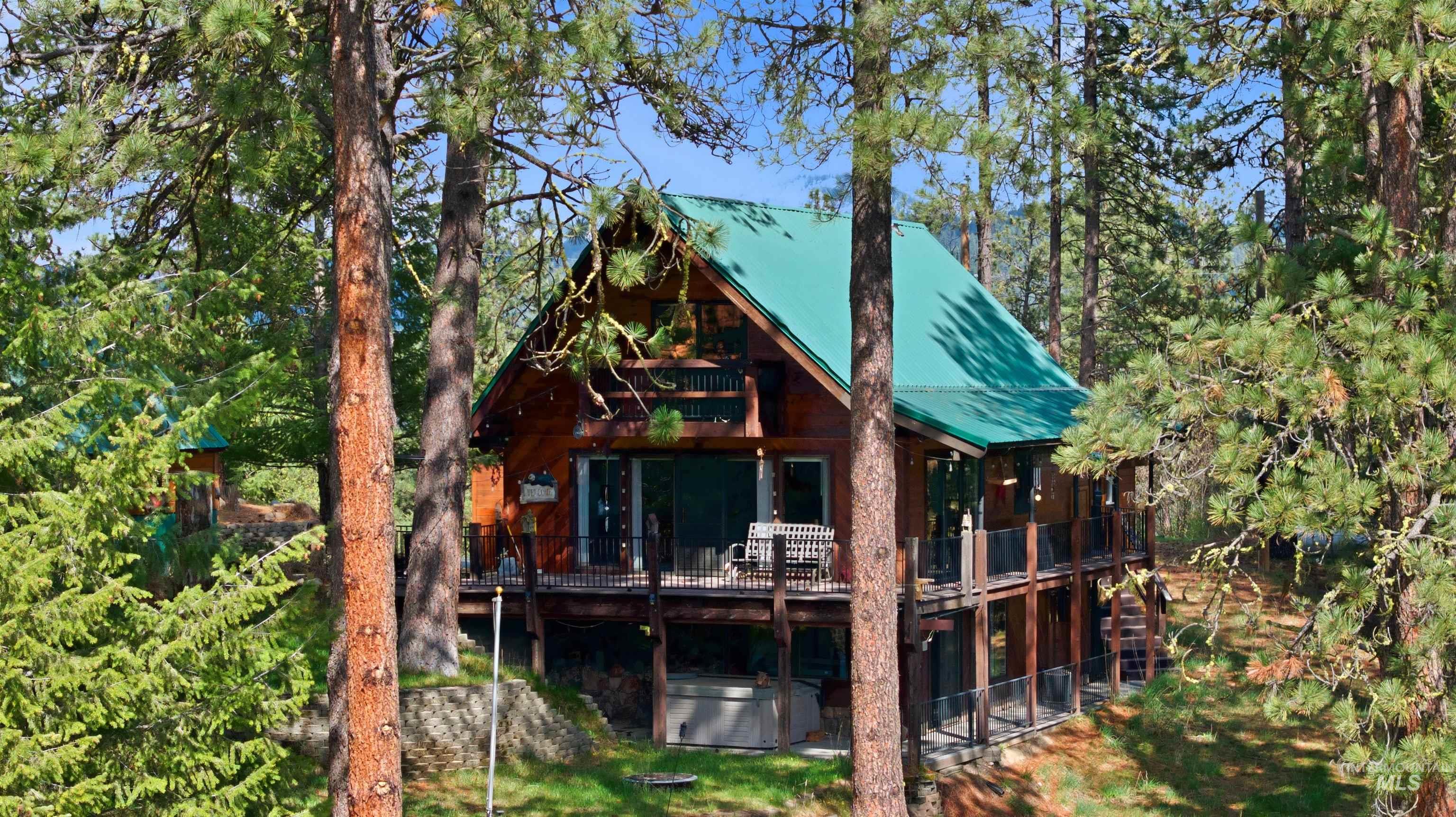 45 Rainbow Ridge Road Garden Valley, ID 83622 - Photo 8 of 41 Rear view of house with a hot tub, a deck, and a metal roof