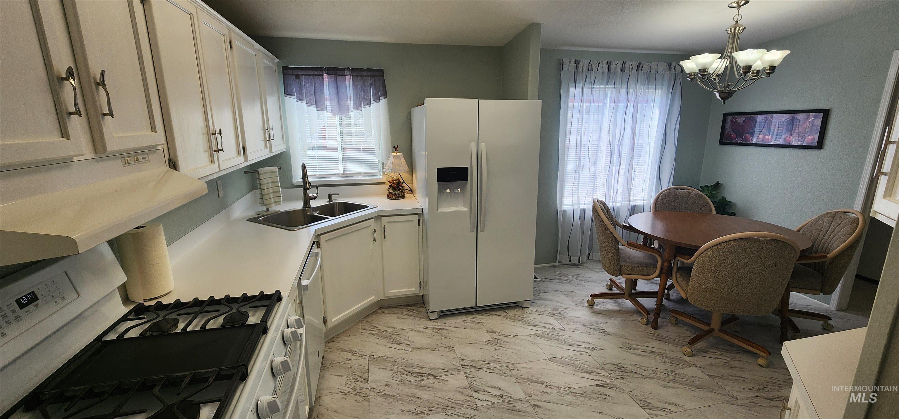 2115 6th Avenue, Unit 51 Clarkston, WA 99403 - Photo 10 of 45 Kitchen featuring white appliances, light marble finish floors, a chandelier, light countertops, and white cabinets