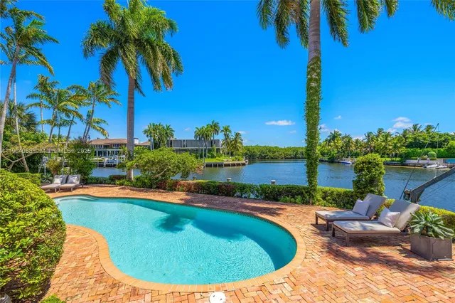 a view of a swimming pool with a yard and palm trees