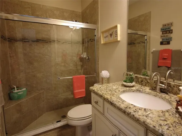 a bathroom with a granite countertop toilet sink and shower
