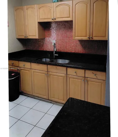 a kitchen with granite countertop a sink a stove and cabinets