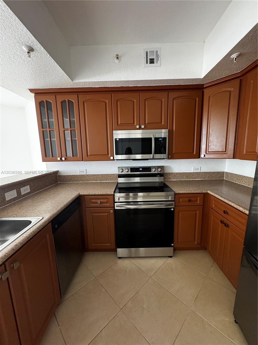 2301 Southwest 27th Avenue, Unit 503 Miami, FL 33145 - Photo 5 of 24 a kitchen with granite countertop a stove top oven microwave and cabinets