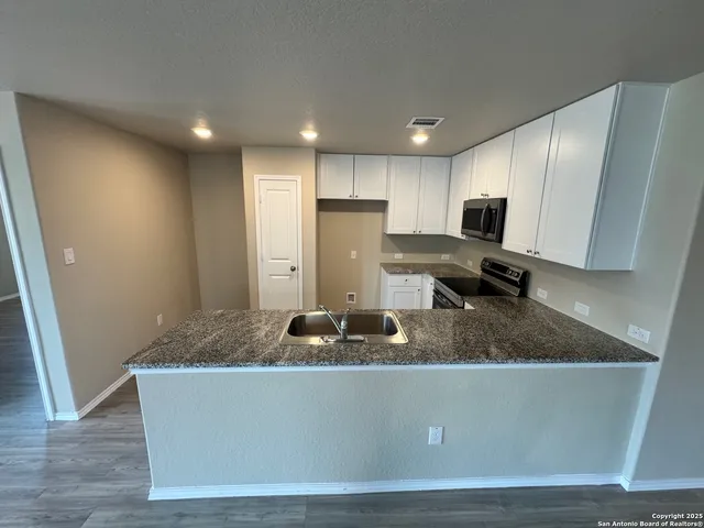 a kitchen with kitchen island stainless steel appliances a sink a refrigerator a stove a microwave and cabinets