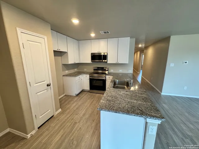 a kitchen with a refrigerator a stove top oven a sink and cabinets