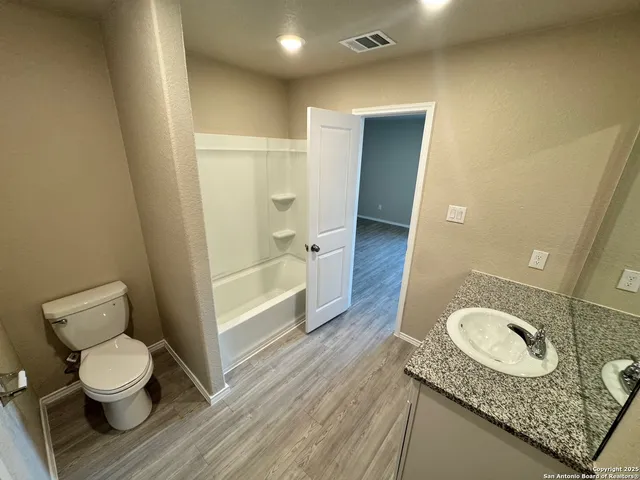 a bathroom with a granite countertop toilet sink and mirror