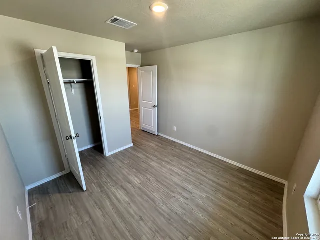 an empty room with wooden floor and a ceiling fan