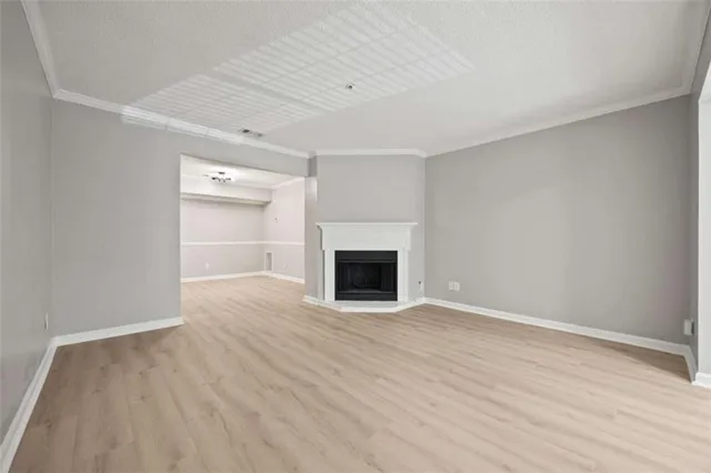 a view of an empty room with wooden floor fireplace and a window