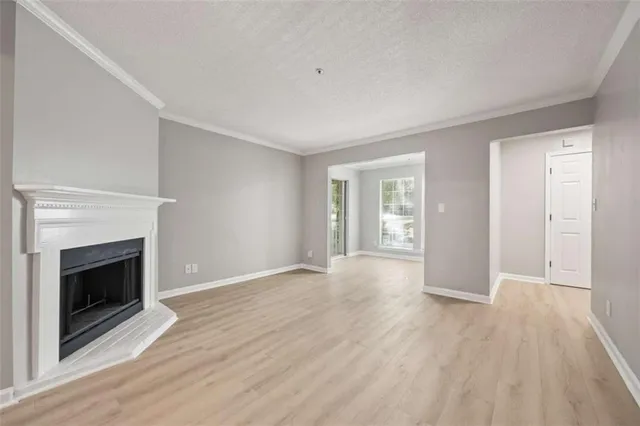 a view of an empty room with wooden floor fireplace and a window