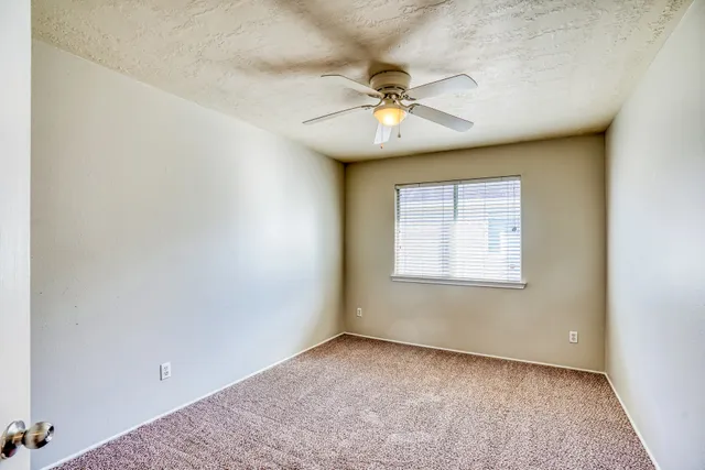 an empty room with a window and a fan