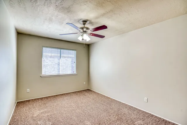 an empty room with a window and a ceiling fan