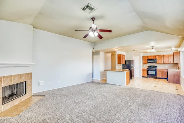 an empty room with kitchen and fireplace