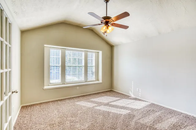 an empty room with a window and a fan