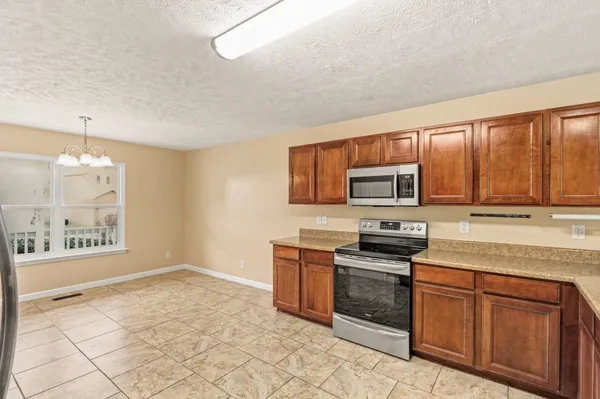 a kitchen with stainless steel appliances granite countertop a stove a sink and a microwave