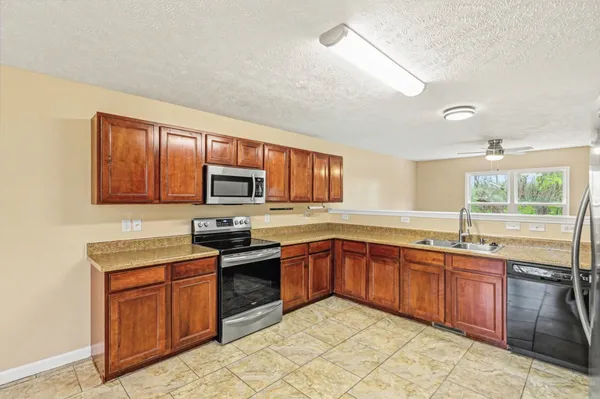 a kitchen with stainless steel appliances granite countertop wooden cabinets a sink and dishwasher a stove top oven with wooden floor