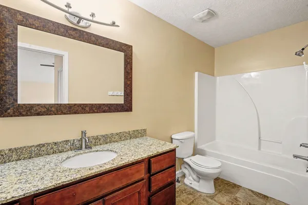 a bathroom with a granite countertop toilet sink and mirror