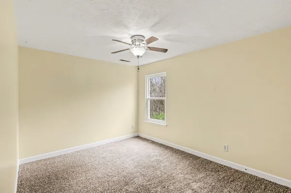 an empty room with windows and fan