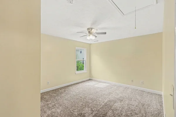 an empty room with a ceiling fan and carpet