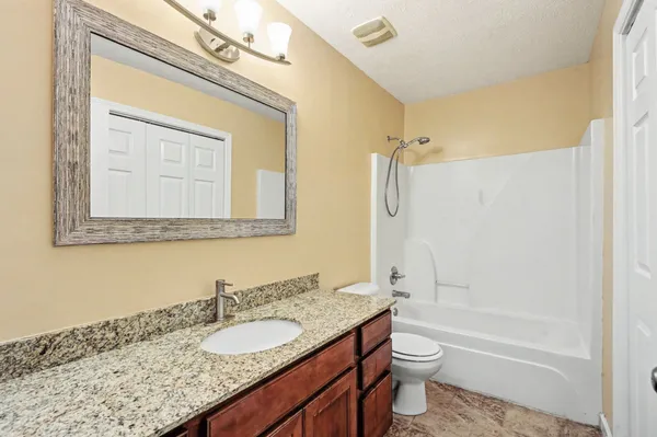 a bathroom with a granite countertop sink toilet and shower