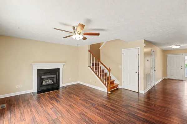 a view of an empty room with wooden floor and a fireplace