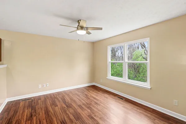 a view of an empty room with wooden floor and a window