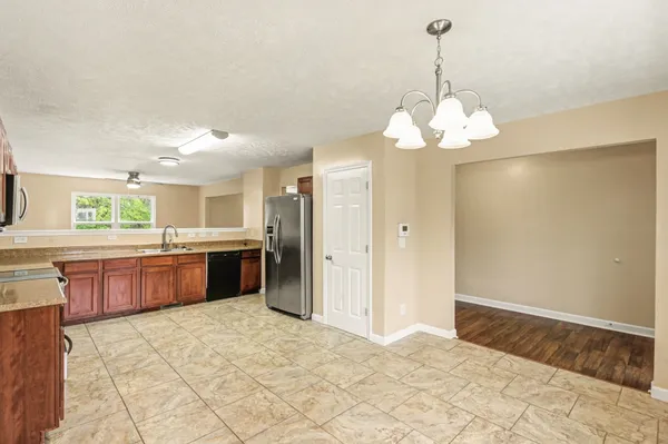 a large kitchen with stainless steel appliances granite countertop a refrigerator a sink dishwasher a oven and a dining table with wooden floor