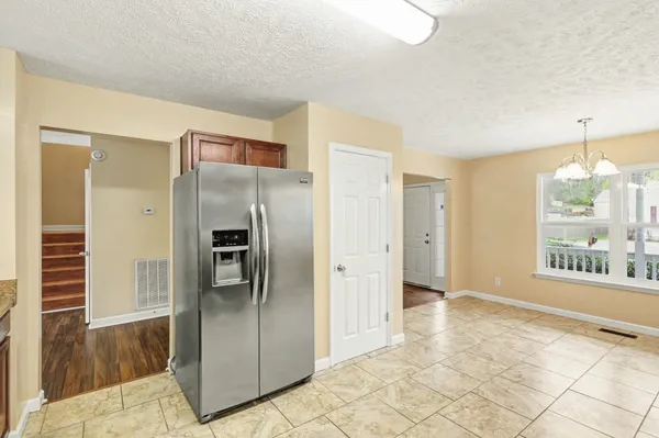 a view of a refrigerator in kitchen and an empty room with windows