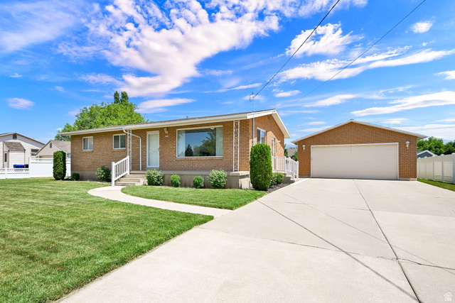 2467 South 2000 West Syracuse, UT 84075 - Photo 4 of 28 Brick exterior home featuring a concrete driveway, detached garage, and a manicured lawn