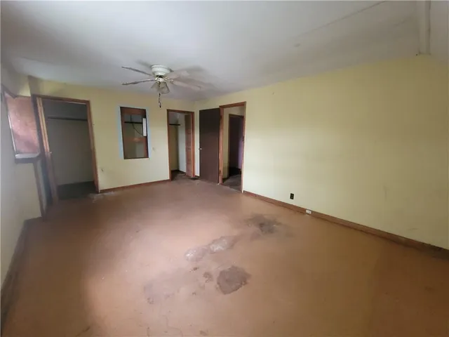 an empty room with chandelier fan and windows