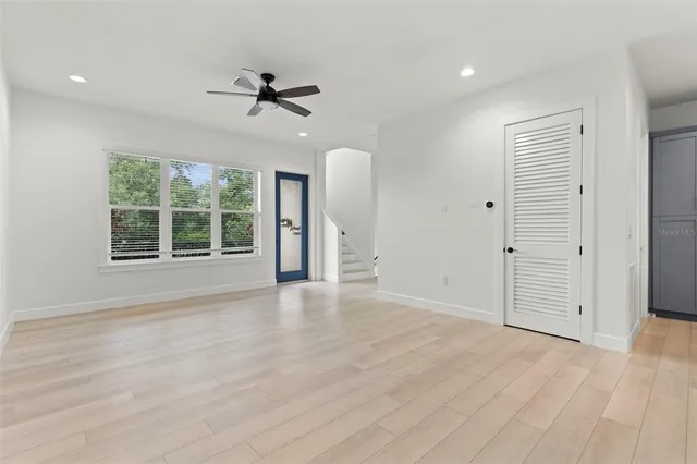 an empty room with windows and chandelier fan
