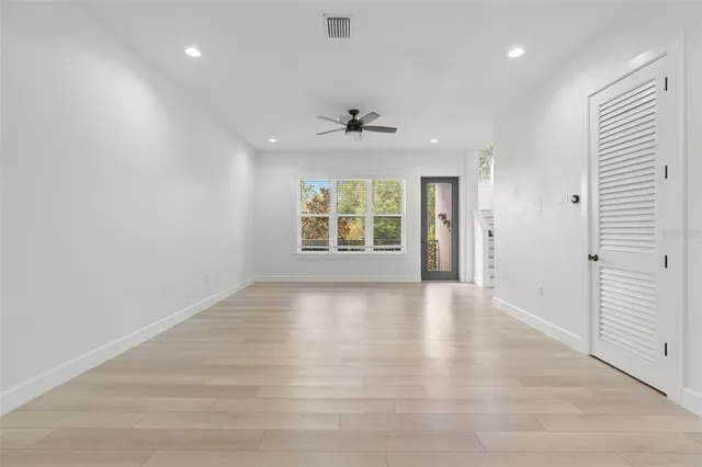 an empty room with wooden floor and windows
