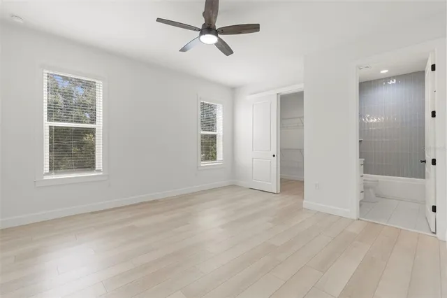 an empty room with a window and a ceiling fan