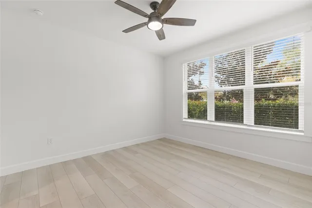 an empty room with wooden floor and a ceiling fan