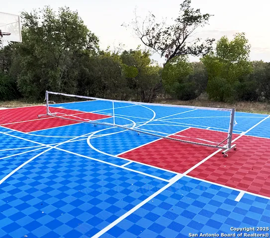 a view of tennis court with seating space and trees in the background